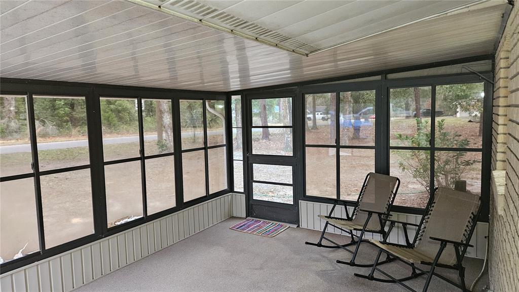 A screened-in porch features gray flooring, a screen door, and large windows overlooking a yard — 662 N CHARLES AVENUE, INVERNESS, FL