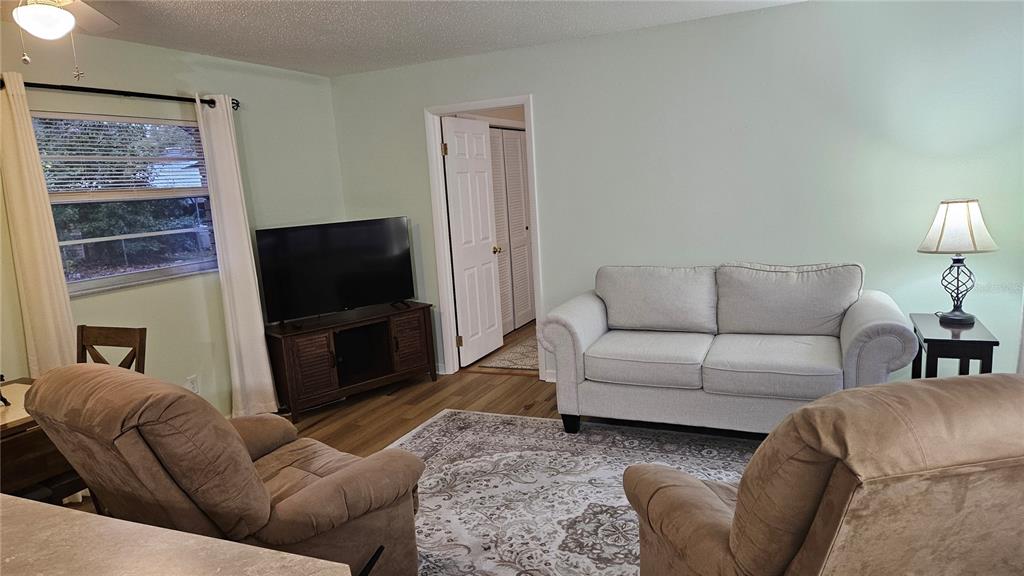 A living room features a light gray sofa, two brown recliners, and a television console — 662 N CHARLES AVENUE, INVERNESS, FL