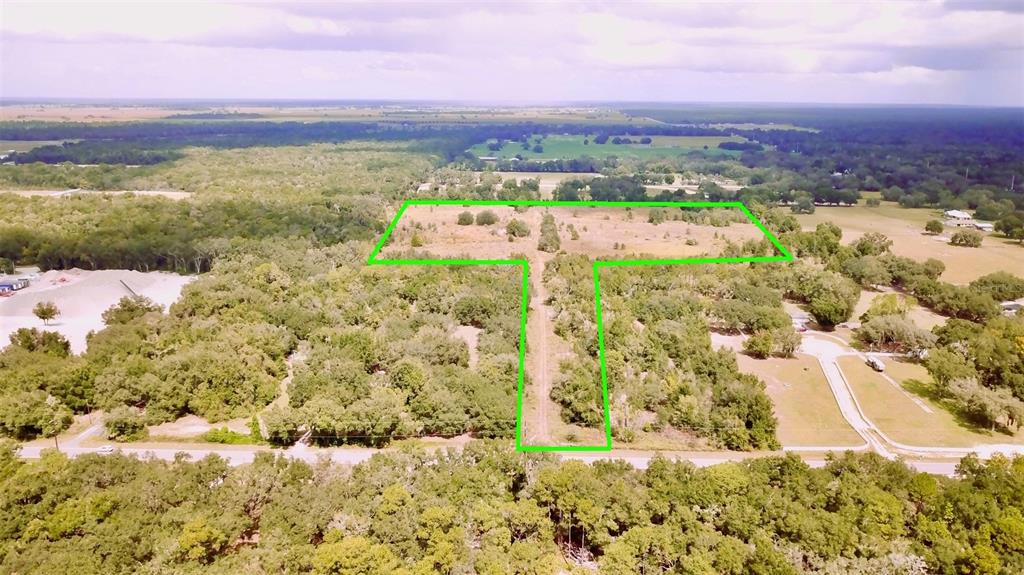 An aerial view shows a T-shaped plot of land outlined in green amidst wooded surroundings — 14385 SW HIGHWAY 484, DUNNELLON, FL