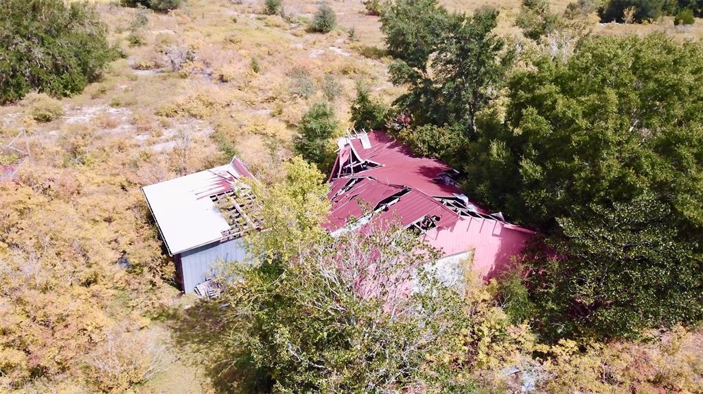 An aerial view shows two dilapidated buildings with damaged metal roofs surrounded by overgrown vegetation — 14385 SW HIGHWAY 484, DUNNELLON, FL