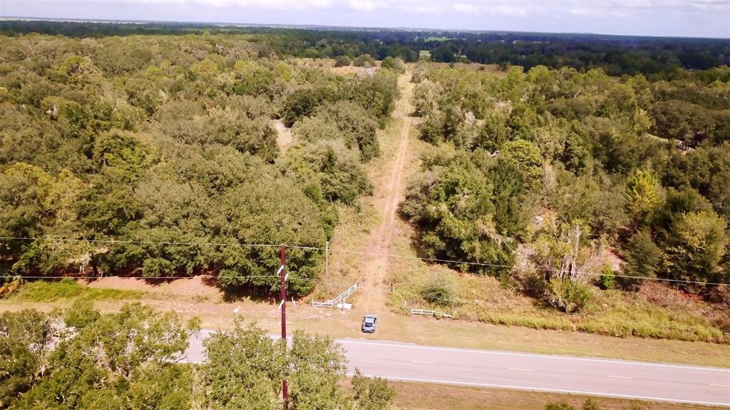 An aerial view shows a dirt path leading into a wooded lot from a paved road — 14385 SW HIGHWAY 484, DUNNELLON, FL