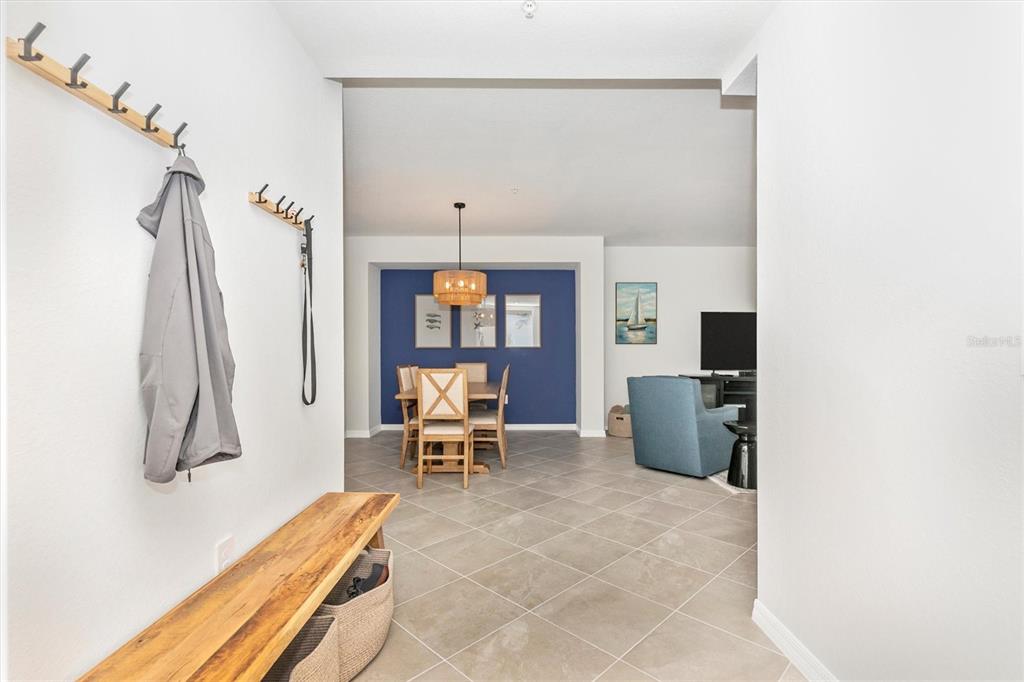 An entryway with a wooden bench and coat hooks leads into an open dining area — 12685 RADIANCE COURT UNIT 102, VENICE, FL