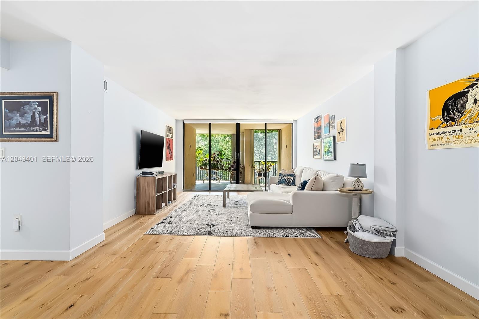 A bright living room features light wood flooring, a white sectional sofa, and a balcony — 2808 N 46th Ave # E549, Hollywood FL 33021, HOLLYWOOD, FL