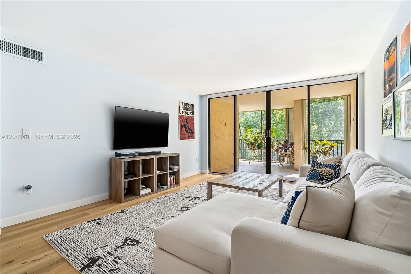A living room features a white sectional sofa, a television on a wooden console, and a balcony — 2808 N 46th Ave # E549, Hollywood FL 33021, HOLLYWOOD, FL
