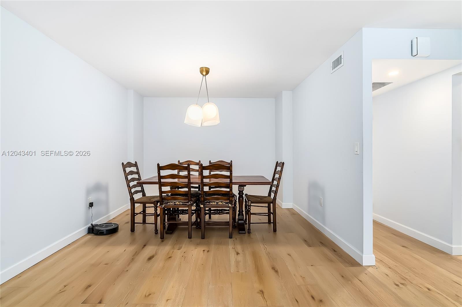 A dining room features a wooden table with six chairs, light wood flooring, and a pendant light — 2808 N 46th Ave # E549, Hollywood FL 33021, HOLLYWOOD, FL