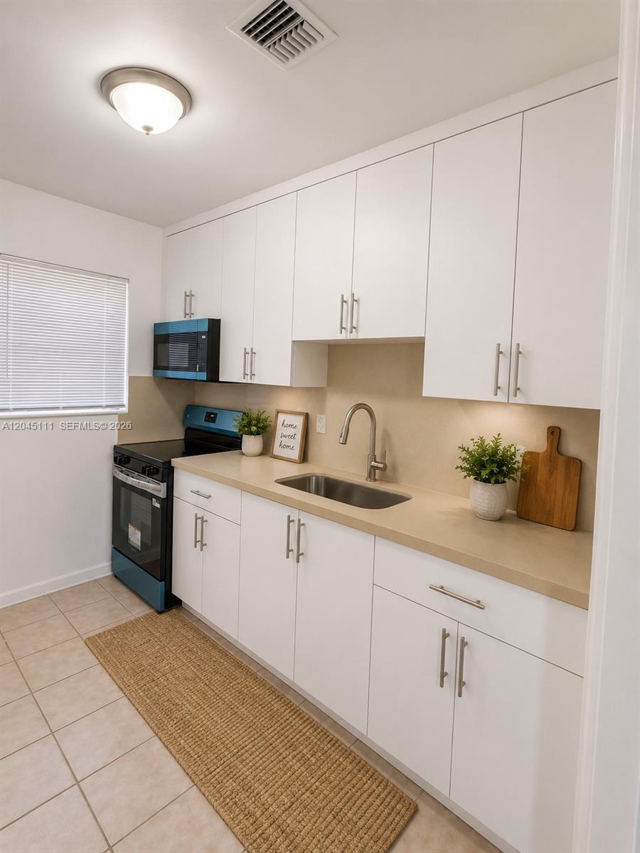 A kitchen features white cabinets, a light countertop, a stainless steel sink, and black appliances — 11601 Pinkston Dr, Miami FL 33176, MIAMI, FL