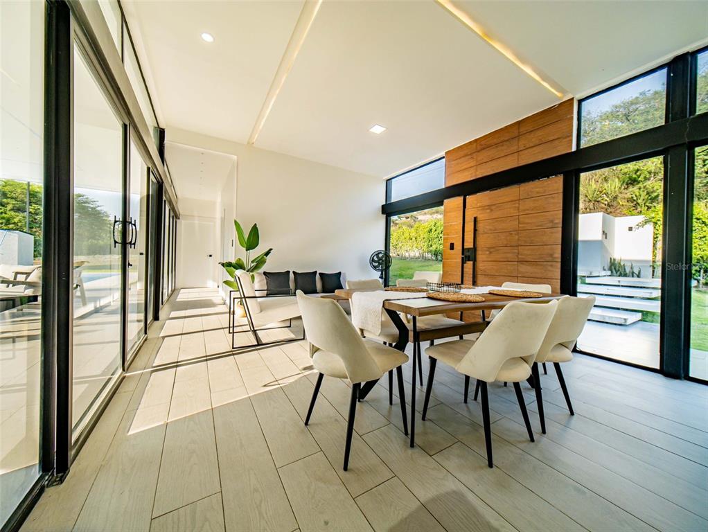 A modern dining room features floor-to-ceiling glass walls, light tile flooring, and wood paneling — 00 CEIBOPAMBA BARRIO EL ALGODONAL, LOJA/ ECUADOR, NY