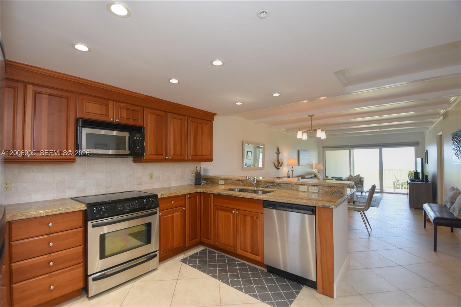 A kitchen features wood cabinets, granite countertops, stainless steel appliances, and an open floor plan — 3101 S Ocean Blvd # 118, Highland Beach FL 33487, HIGHLAND BEACH, FL