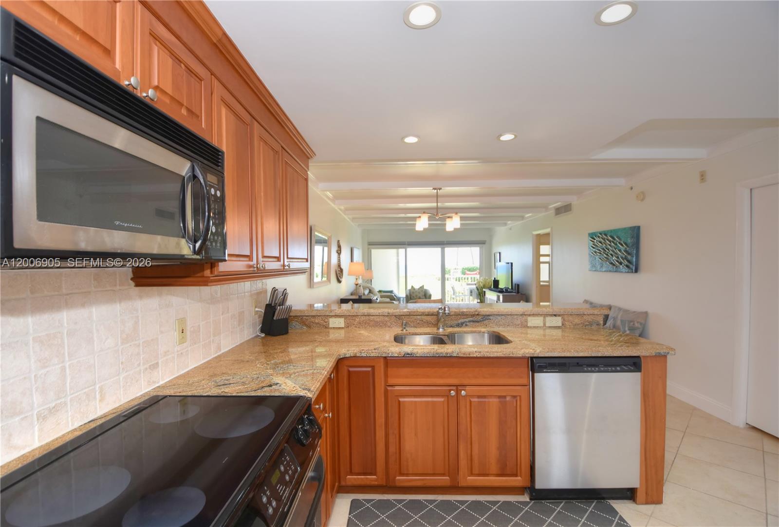 A kitchen features wood cabinets, granite countertops, stainless steel appliances, and a view into the living area — 3101 S Ocean Blvd # 118, Highland Beach FL 33487, HIGHLAND BEACH, FL