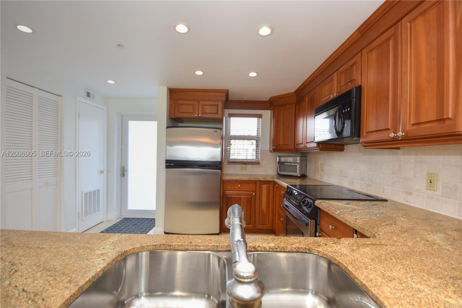 A kitchen features wood cabinets, granite countertops, stainless steel appliances, and a double sink — 3101 S Ocean Blvd # 118, Highland Beach FL 33487, HIGHLAND BEACH, FL