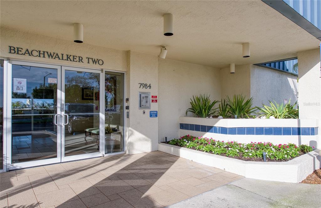 The exterior entrance of a building features glass double doors and a landscaped planter — 7984 SAILBOAT KEY BOULEVARD S UNIT 502, SOUTH PASADENA, FL