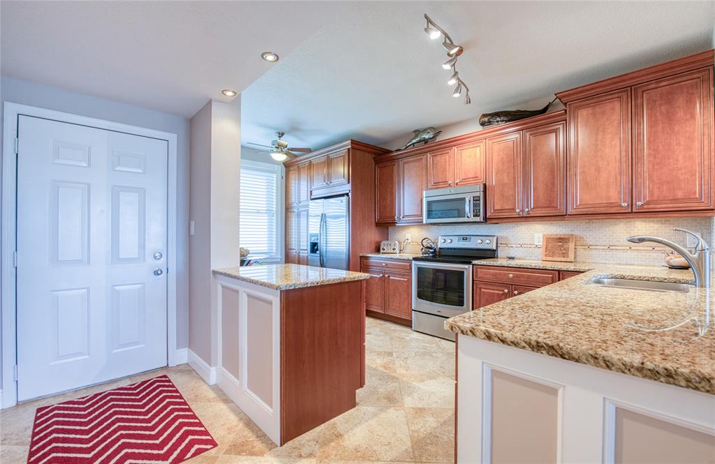 A kitchen features cherry wood cabinets, granite countertops, stainless steel appliances, and tile flooring — 7984 SAILBOAT KEY BOULEVARD S UNIT 502, SOUTH PASADENA, FL