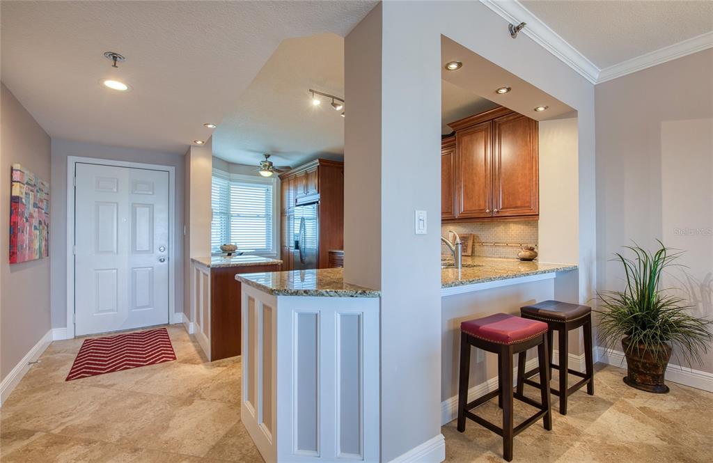 A kitchen with granite countertops, wooden cabinets, and a breakfast bar with two stools — 7984 SAILBOAT KEY BOULEVARD S UNIT 502, SOUTH PASADENA, FL