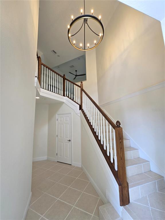 A bright foyer features a tiled floor, a wooden staircase, and a large circular chandelier — 4118 OSPREY HARBOUR LOOP, CORTEZ, FL