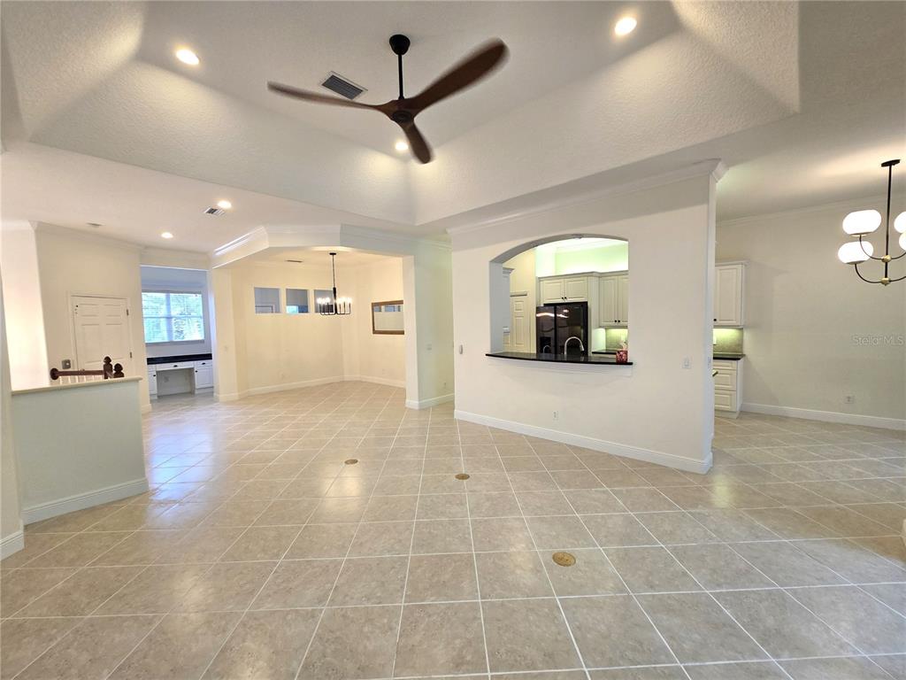 An open-concept living area features a tray ceiling, tile flooring, and a kitchen pass-through — 4118 OSPREY HARBOUR LOOP, CORTEZ, FL