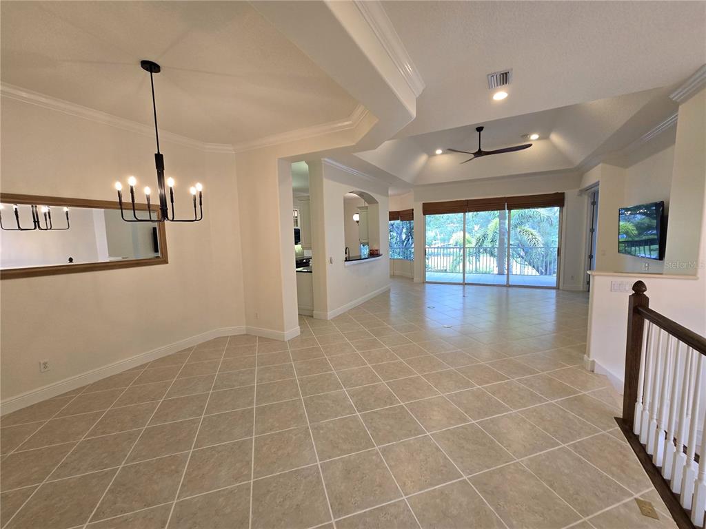 A dining area with tile floors leads to a living room with a tray ceiling — 4118 OSPREY HARBOUR LOOP, CORTEZ, FL