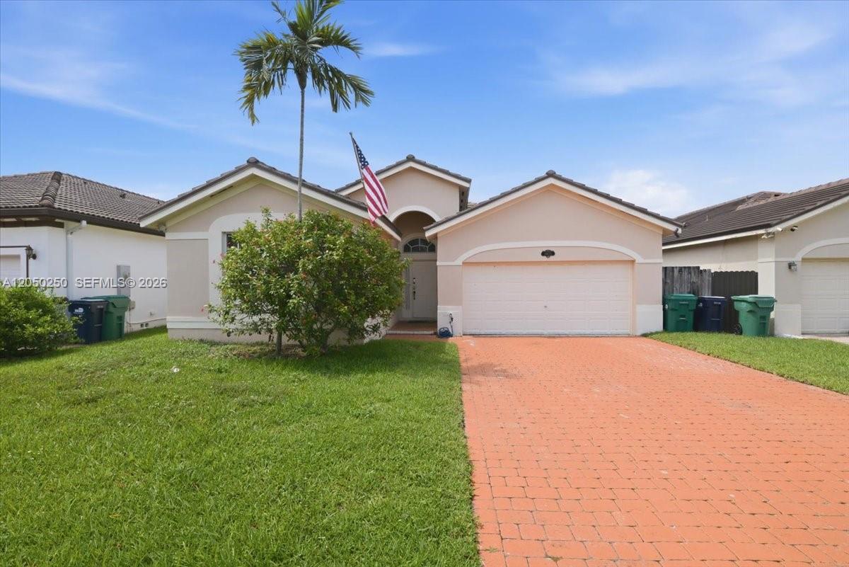 A single-story house features a brick paver driveway, a palm tree, and an American flag — 14623 SW 11th St, Miami FL 33184, MIAMI, FL