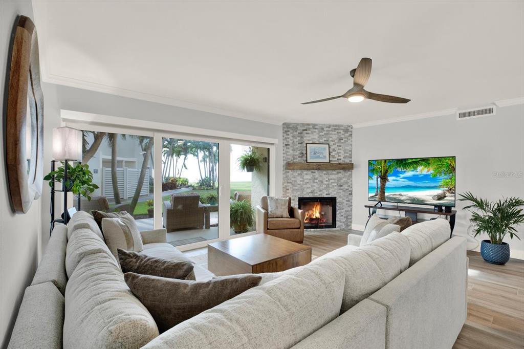 A living room features a corner stone fireplace, a large sectional sofa, and sliding glass doors — 7530 SUNSHINE SKYWAY LANE S UNIT P7, ST PETERSBURG, FL