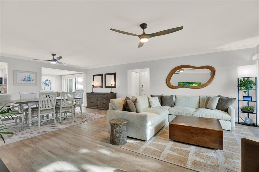 An open-concept living and dining area features light wood-look tile flooring and neutral furniture — 7530 SUNSHINE SKYWAY LANE S UNIT P7, ST PETERSBURG, FL