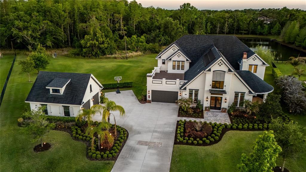An aerial view shows a white two-story house with a detached garage and driveway — 19101 MAGNOLIA FARMS LANE, ODESSA, FL