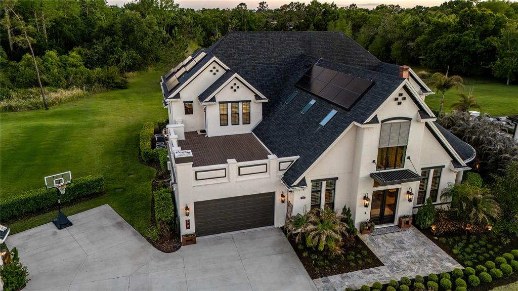An aerial view shows a two-story house with a garage, balcony, and solar panels — 19101 MAGNOLIA FARMS LANE, ODESSA, FL