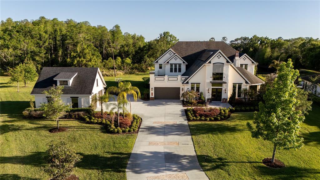 A large white two-story house with a detached garage sits on a grassy lot — 19101 MAGNOLIA FARMS LANE, ODESSA, FL