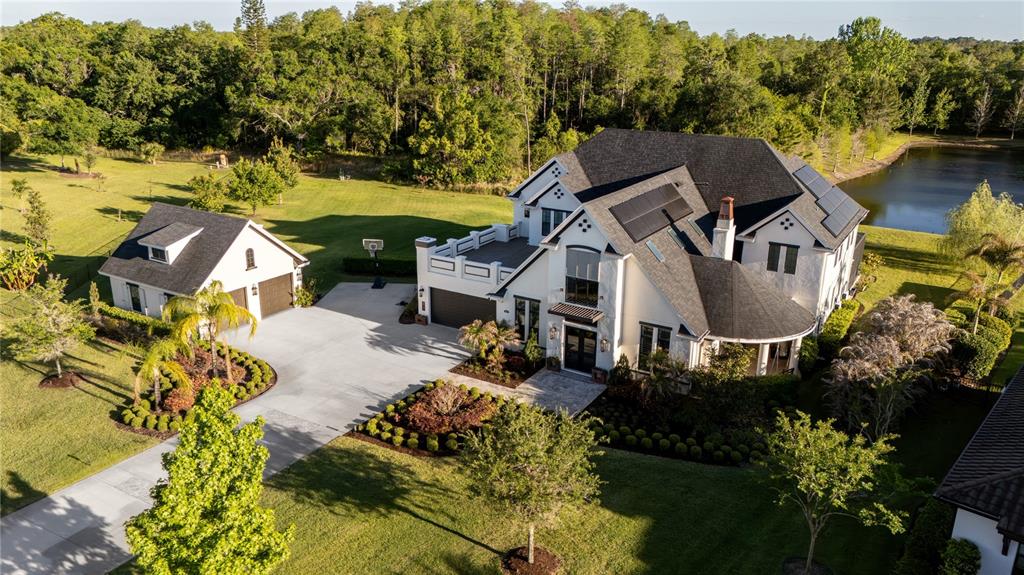 An aerial view shows a white two-story house with a detached garage and solar panels — 19101 MAGNOLIA FARMS LANE, ODESSA, FL