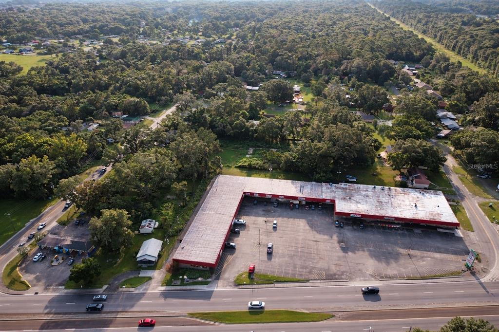 An aerial view shows an L-shaped commercial strip mall with a large parking lot — 942 NE 35TH STREET, OCALA, FL