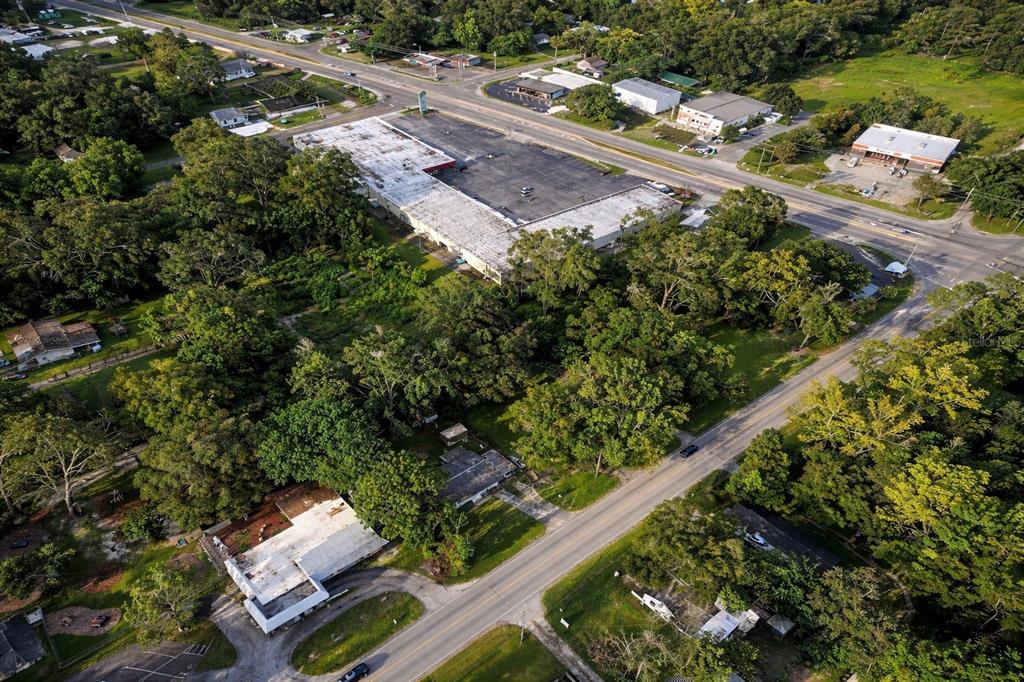 An aerial view shows a large commercial building surrounded by trees and residential properties — 942 NE 35TH STREET, OCALA, FL