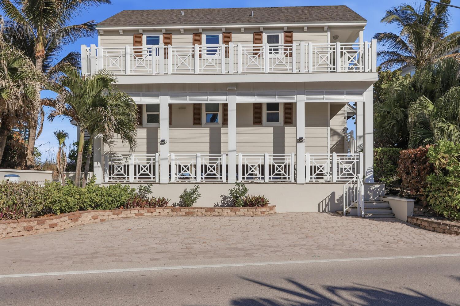 A two-story house with beige siding, white railings, and a paved driveway — 1031 SE Macarthur Boulevard, Stuart FL 34996, STUART, FL