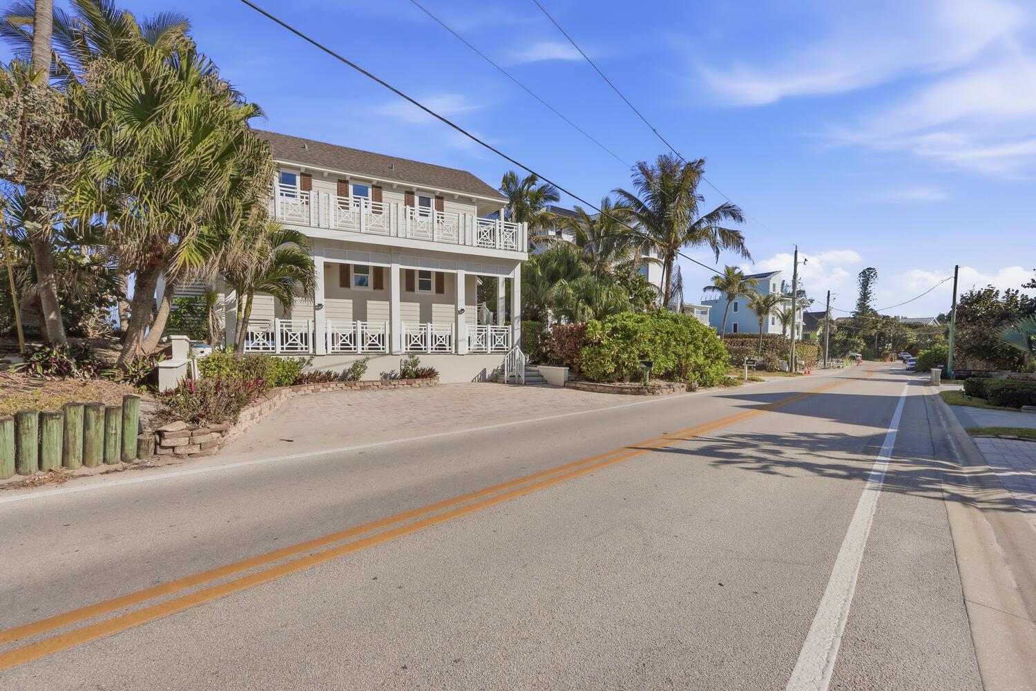 A two-story house with a white porch and balcony sits beside a paved road — 1031 SE Macarthur Boulevard, Stuart FL 34996, STUART, FL