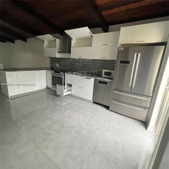 A modern kitchen features white flat-panel cabinetry, stainless steel appliances, and large grey floor tiles — 112 Fox Rd # 50, Hollywood FL 33024, HOLLYWOOD, FL