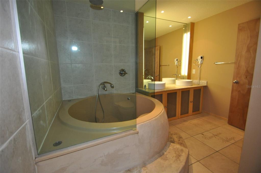 A bathroom features a circular soaking tub, a glass shower partition, and a double vanity — 101 PALM HARBOR PARKWAY UNIT C230, PALM COAST, FL