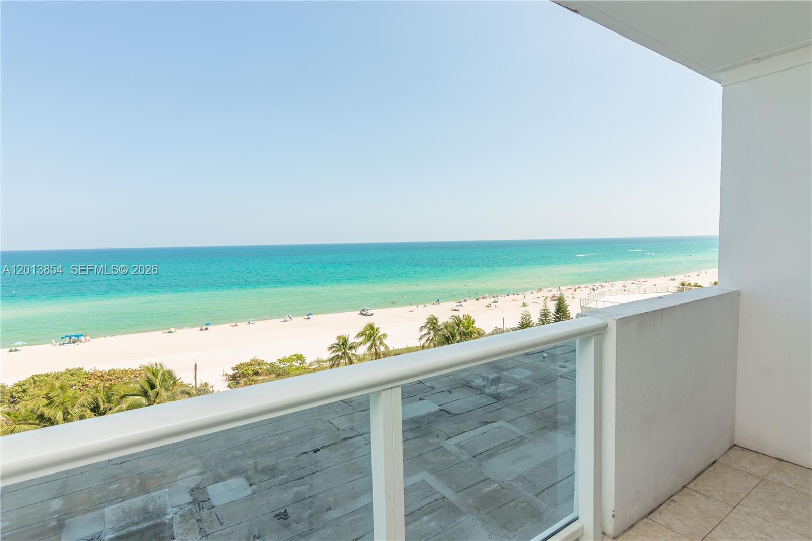 A balcony overlooks a sandy beach and the ocean under a clear blue sky — 5445 Collins Ave # 627, Miami Beach FL 33140, MIAMI BEACH, FL