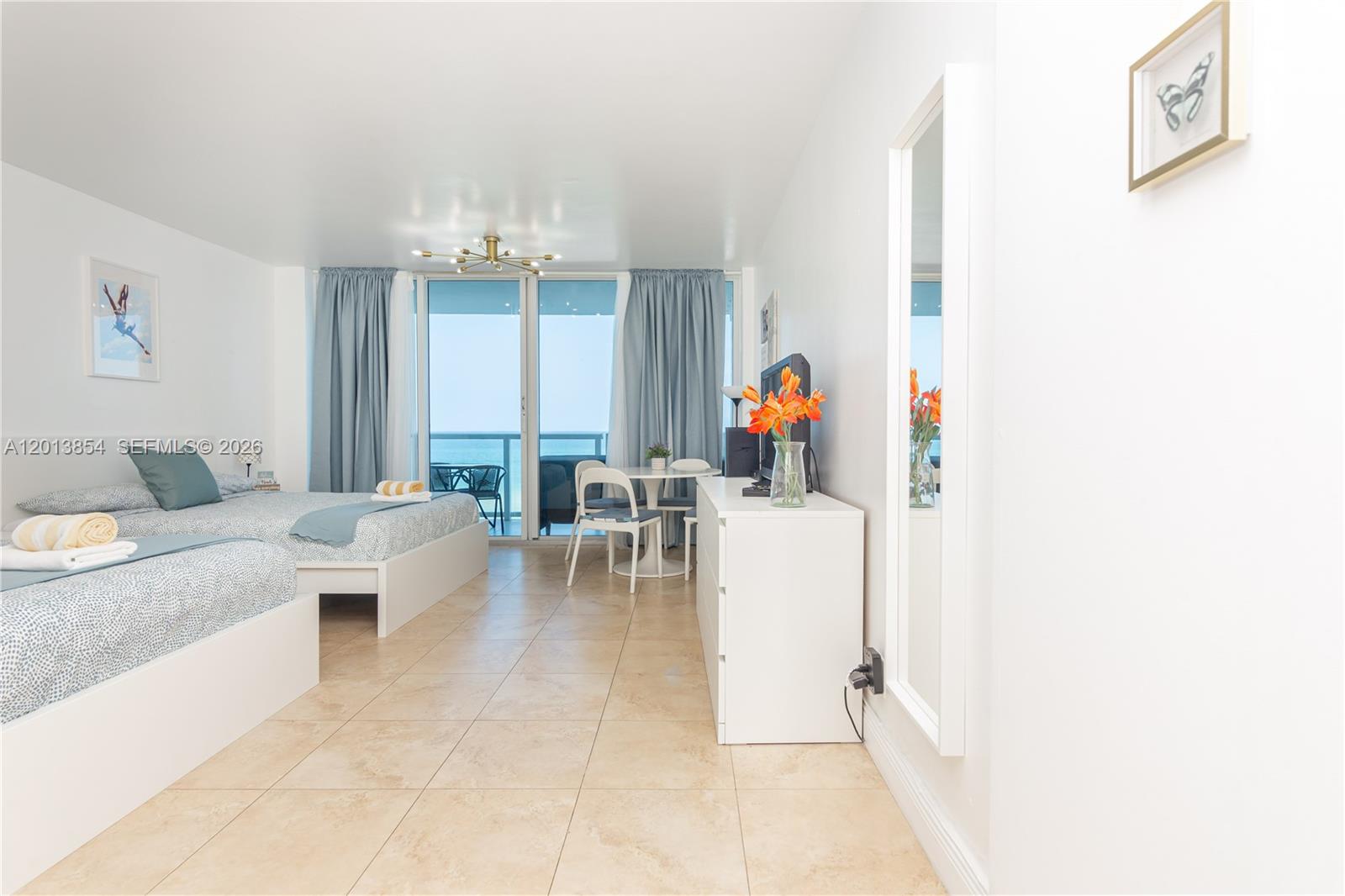 This bedroom features two beds, a dining area, and a balcony overlooking the ocean — 5445 Collins Ave # 627, Miami Beach FL 33140, MIAMI BEACH, FL