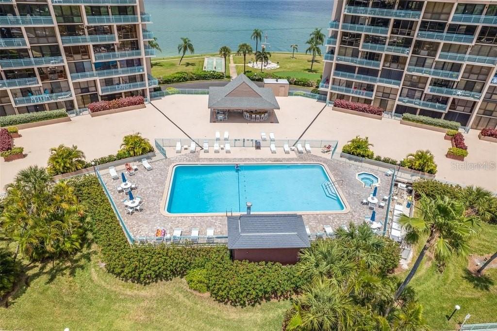 An aerial view shows a swimming pool, a covered pavilion, and two large residential buildings — 1 KEY CAPRI UNIT 302E, TREASURE ISLAND, FL
