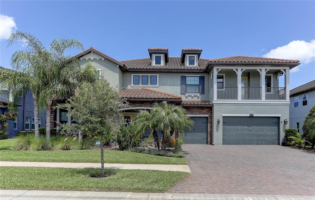 A two-story house with a tile roof, a brick driveway, and a second-floor balcony — 18014 WOODLAND VIEW DRIVE, LUTZ, FL