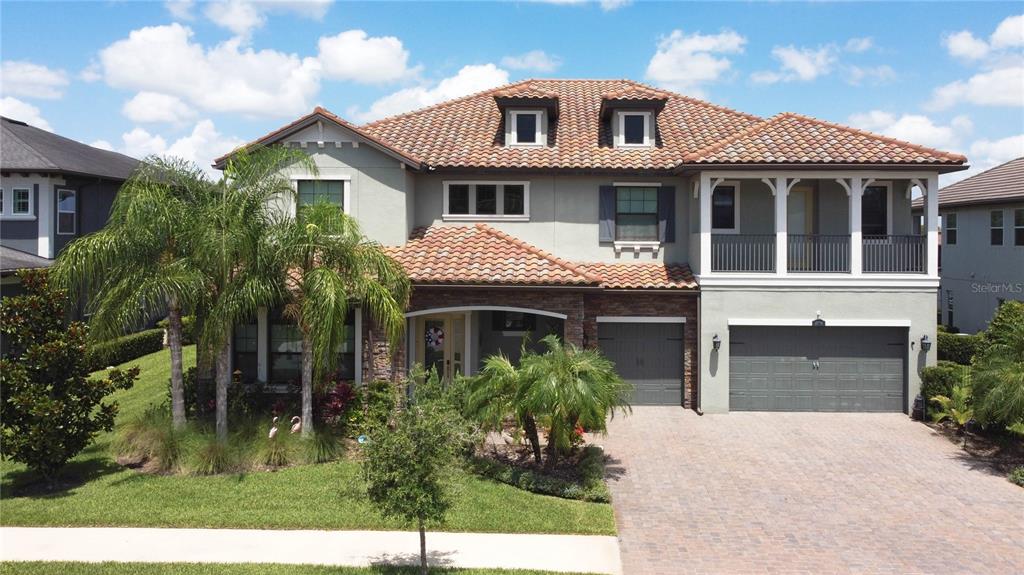 A two-story house with a tiled roof, a two-car garage, and a front balcony — 18014 WOODLAND VIEW DRIVE, LUTZ, FL