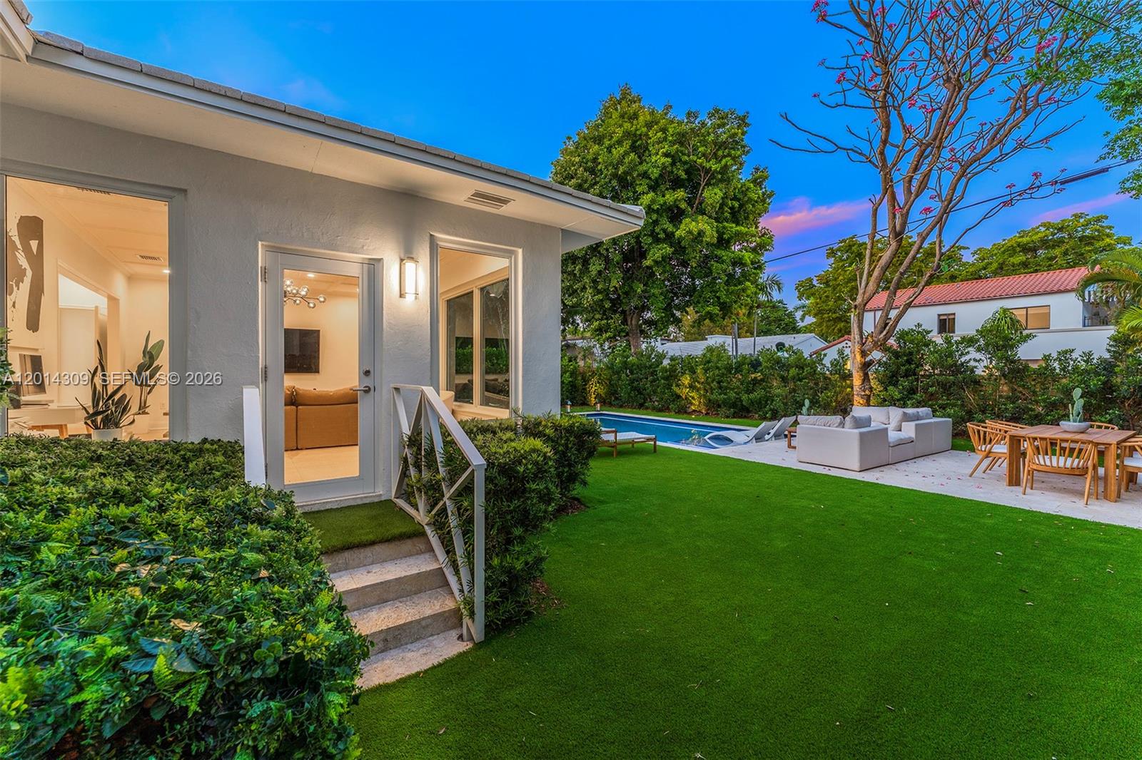 A backyard features a swimming pool, patio furniture, artificial grass, and a white house exterior — 6145 La Gorce Dr, Miami Beach FL 33140, MIAMI BEACH, FL