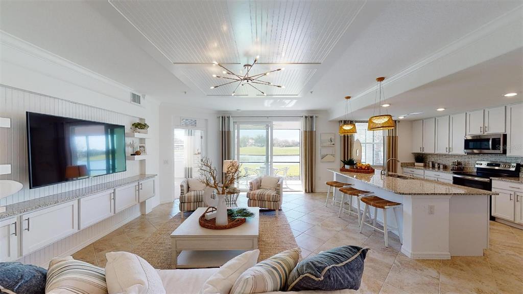 An open-concept living room and kitchen feature tile floors, white cabinetry, and a sliding door — 12913 SANTA MONICA COURT UNIT 74-102, VENICE, FL