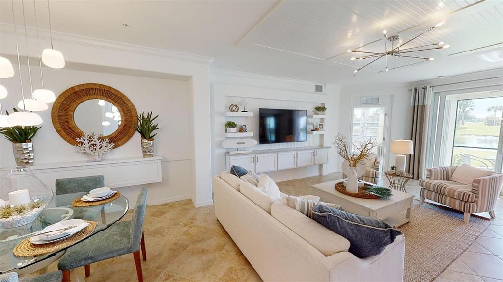 A bright living and dining area features white cabinetry, a television, and coastal decor — 12913 SANTA MONICA COURT UNIT 74-102, VENICE, FL