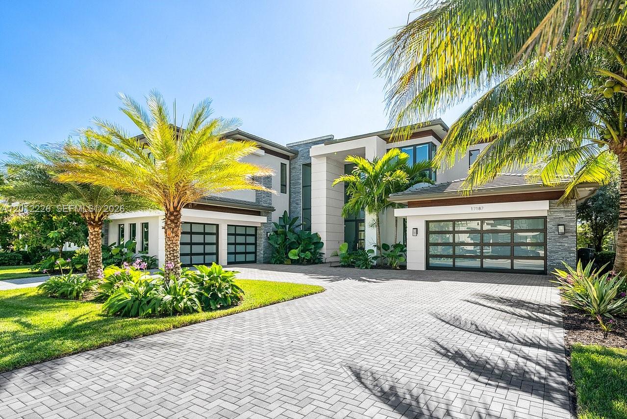 A modern two-story house with a paved driveway, three garage bays, and tropical landscaping — 17187 Brulee Breeze Way, Boca Raton FL 33496, BOCA RATON, FL