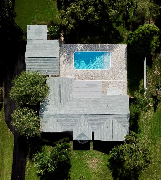 An aerial view shows a house with a gray roof, a pool, and surrounding trees — 1646 ROBIN HOOD LANE, CLEARWATER, FL