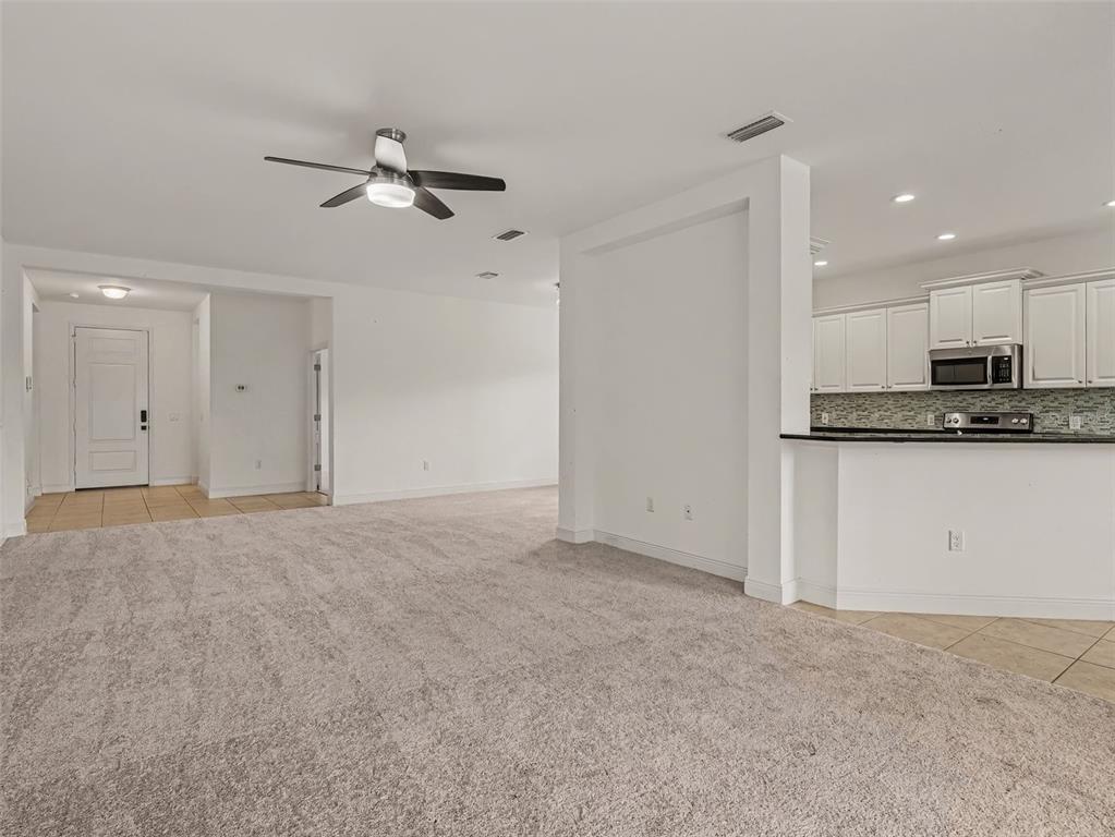 A carpeted living area opens to a kitchen with white cabinets and a breakfast bar — 7521 RIDGELAKE CIRCLE, BRADENTON, FL
