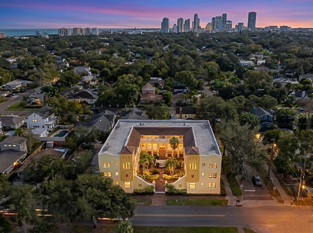 An aerial view shows a U-shaped apartment building with a central courtyard and city skyline — 210 22ND AVENUE NE UNIT 15, ST PETERSBURG, FL