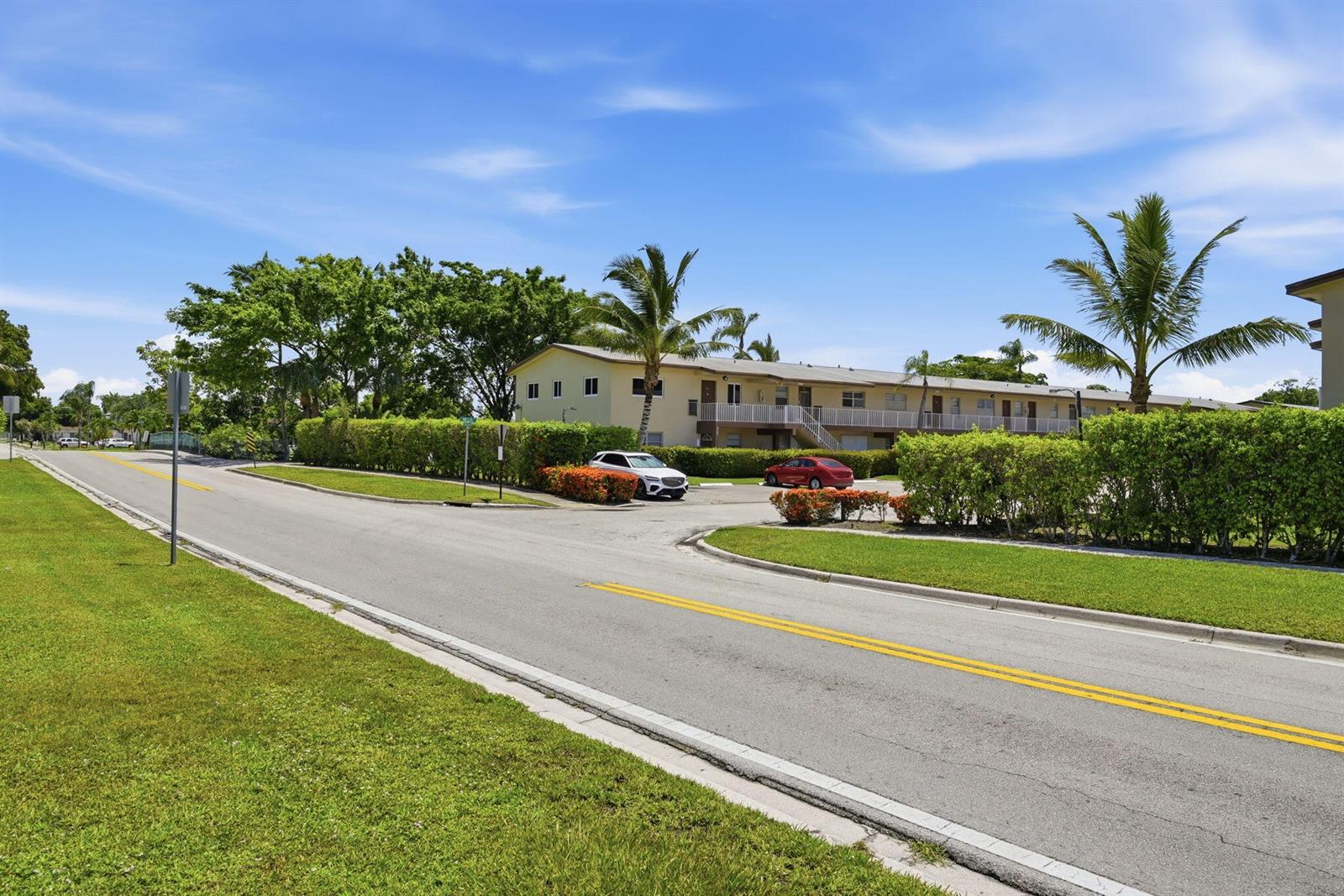 A two-story apartment building sits behind a road with a parking lot and palm trees — 7505 NW 5th Place # 203, Margate FL 33063, MARGATE, FL