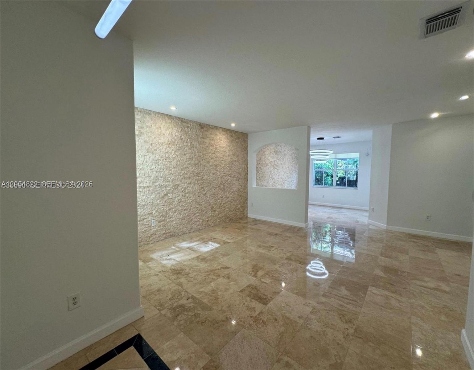 A bright, open living space features polished stone flooring and a textured stone accent wall — 7563 NW 112th Pl, Doral FL 33178, DORAL, FL