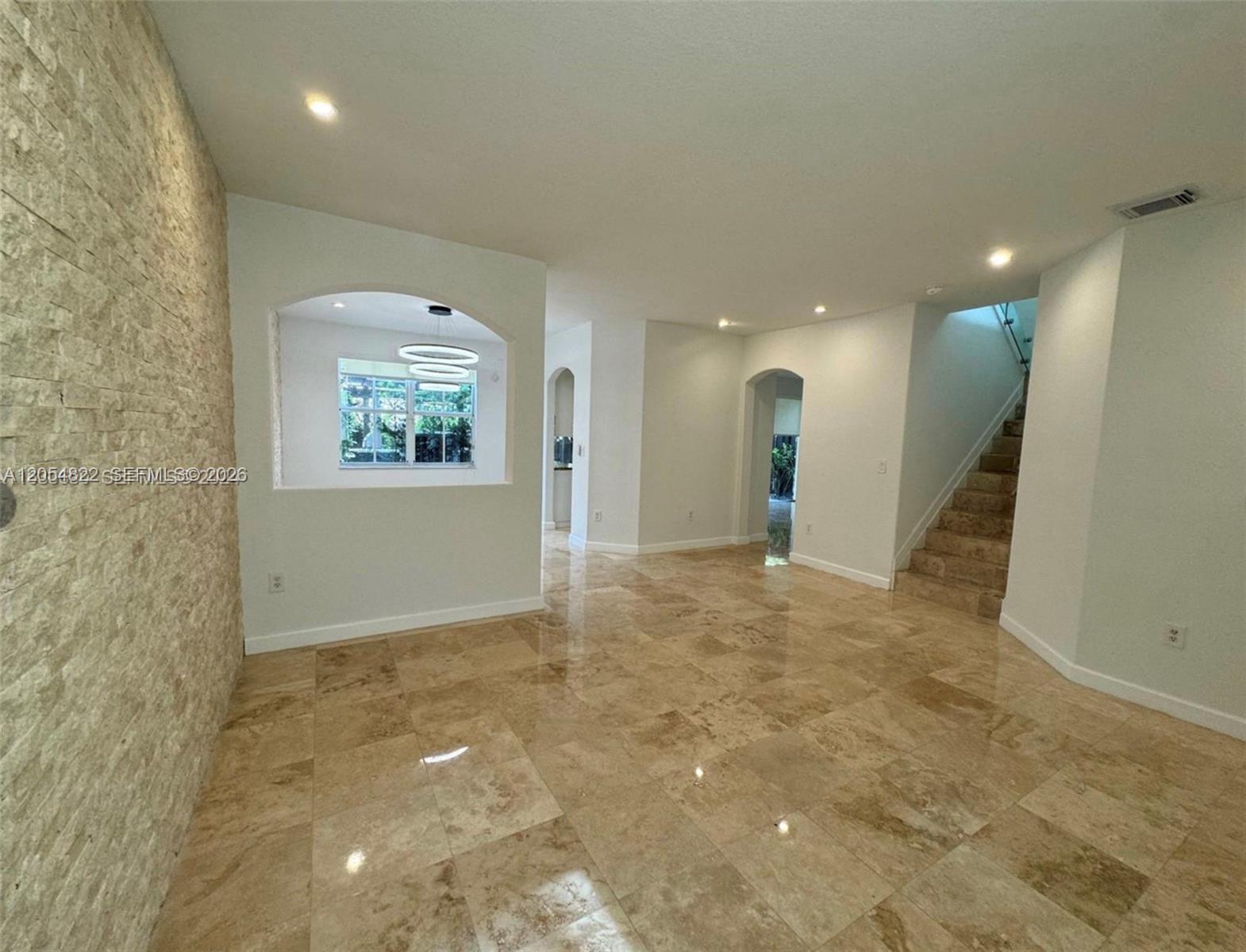 An interior view shows a room with stone-tiled floors, a textured wall, and a staircase — 7563 NW 112th Pl, Doral FL 33178, DORAL, FL