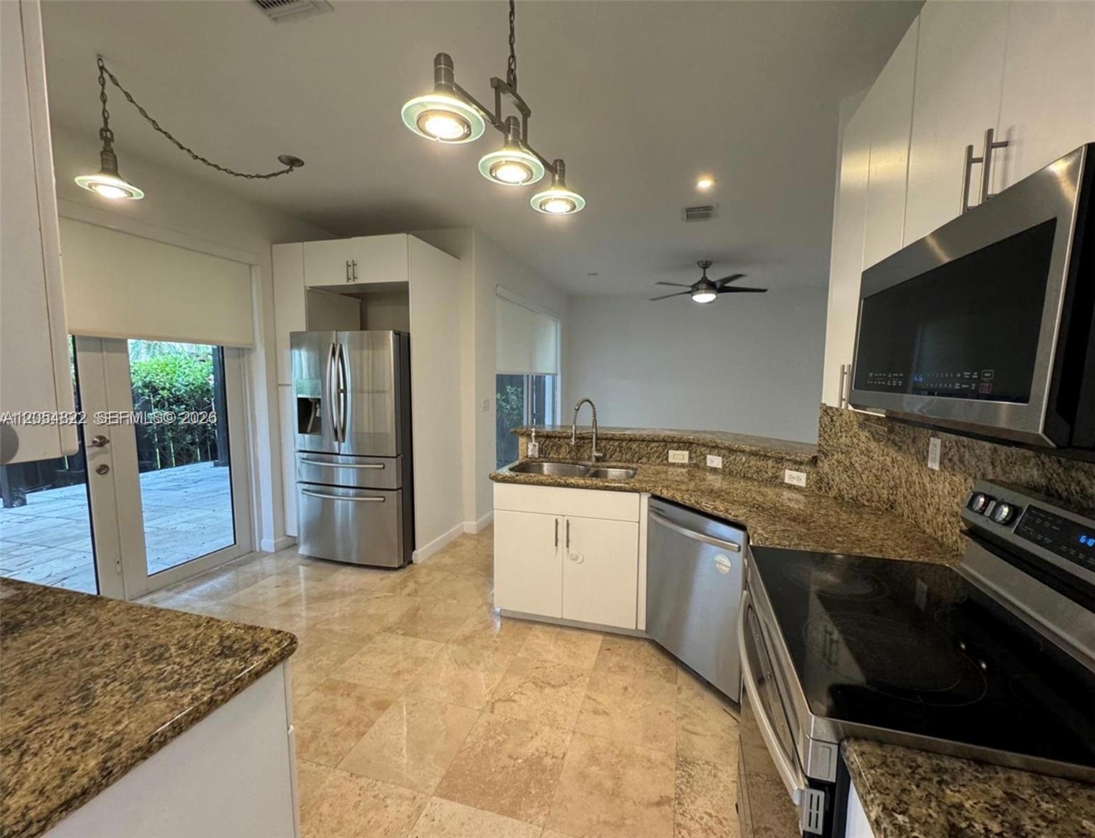 A kitchen features granite countertops, stainless steel appliances, white cabinets, and tile flooring — 7563 NW 112th Pl, Doral FL 33178, DORAL, FL