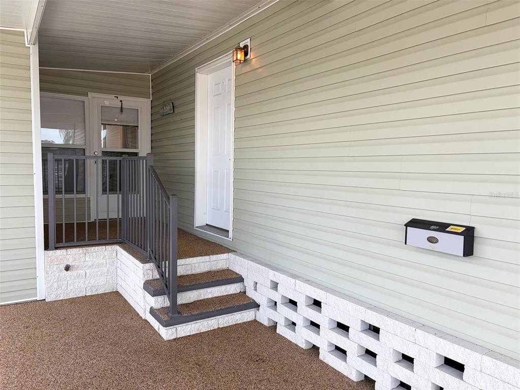 A covered porch features light green siding, white brick steps, and a metal railing — 1503 23RD AVENUE W, BRADENTON, FL